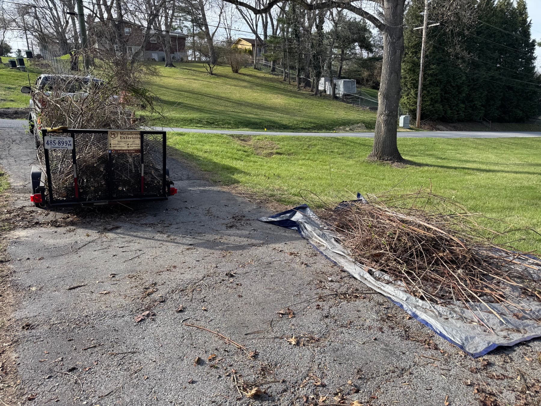 Utility trailer loaded with branches and yard debris after a cleanup job
