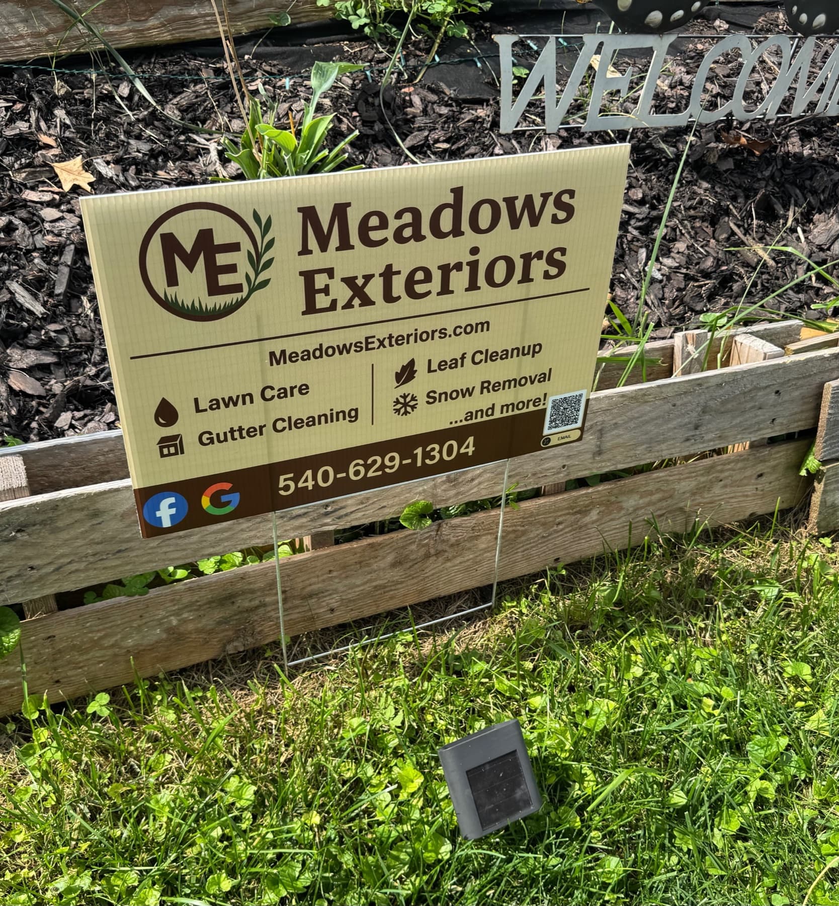 Meadows Exteriors promotional yard sign displaying company logo, services, and contact information